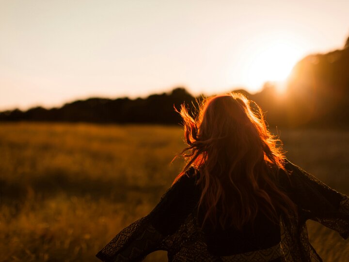 Woman walking in a field at sunset